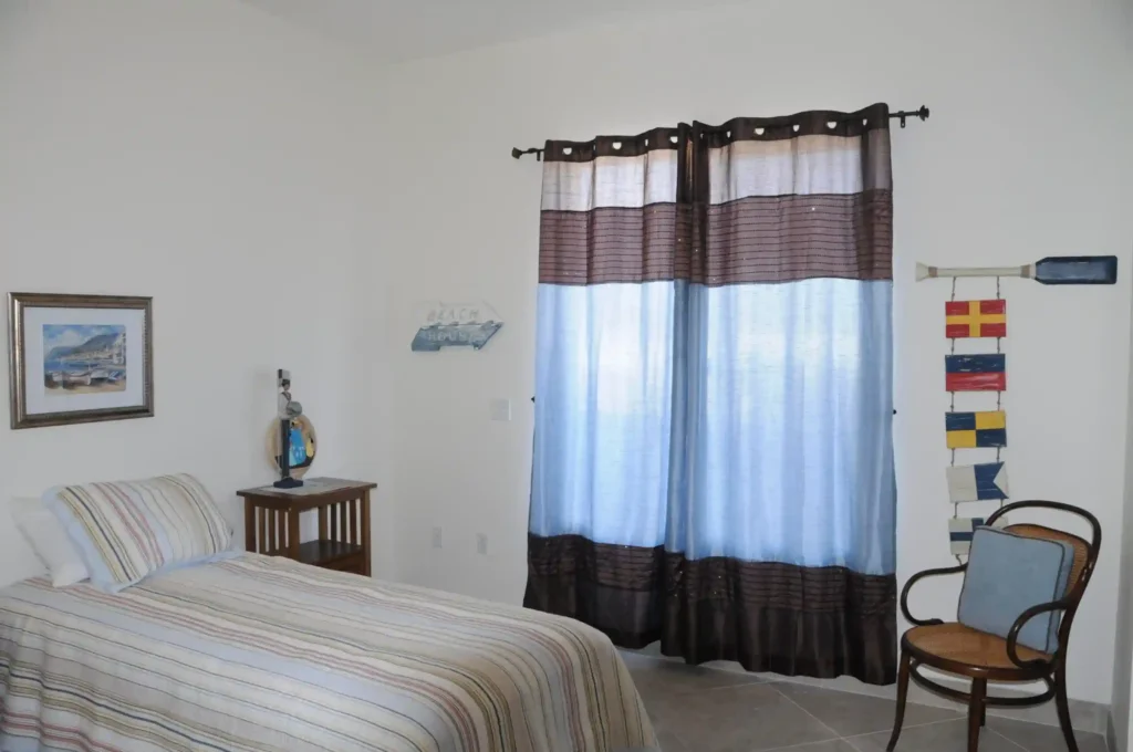 An image in which a bed and a chair with some wall art at Nevada Memory Care