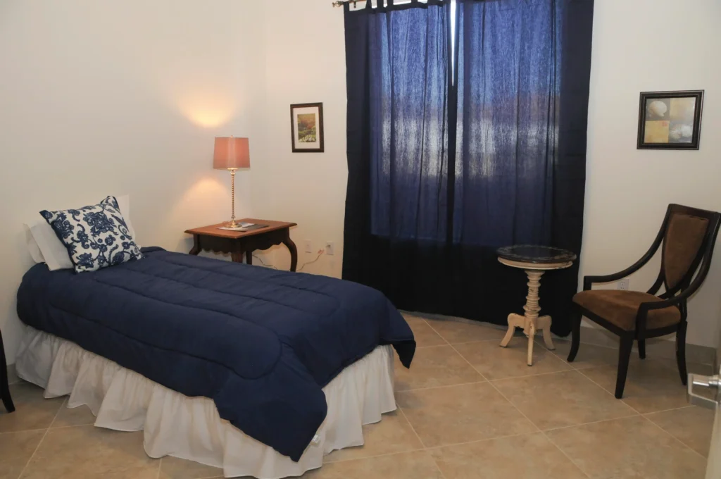 A bed with a blue comforter is featured in the Nevada Memory care facility.