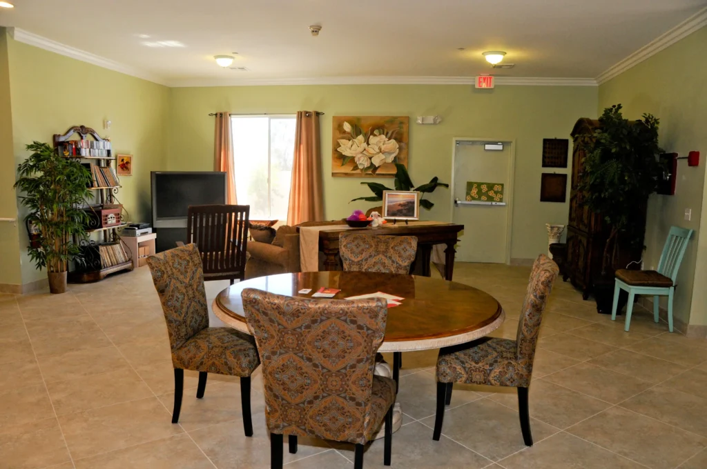 A memory care unit featuring a living room with a table and chairs.